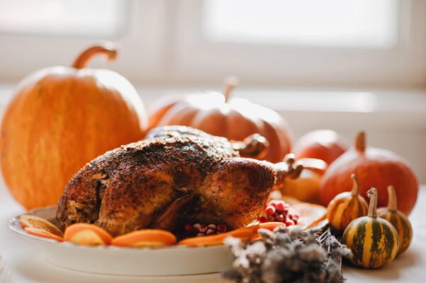 Delicious golden roasted Thanksgiving turkey on dinner table with pumpkins